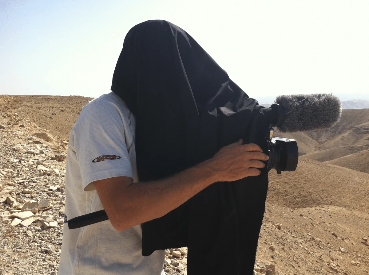Cameraman with black cloth hood over camera in Judean Desert