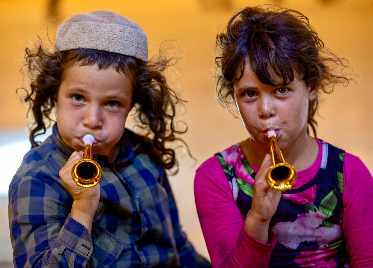 Two children playing trumpets at a festival