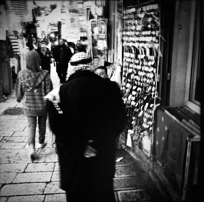 Man in a keffiyeh walking through a crowded market alley, motion blur, Old City, Jerusalem