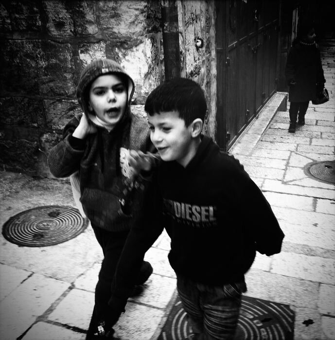 Two children walking arm in arm through an Old City alley, Jerusalem