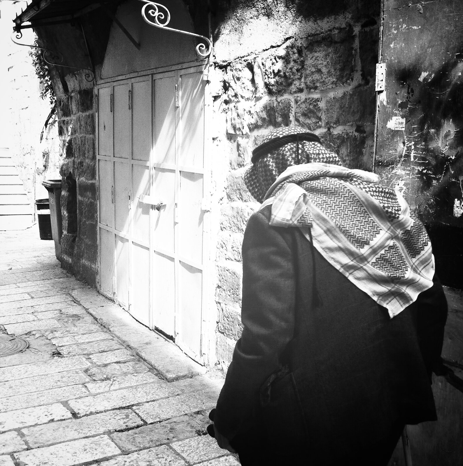 Man in a keffiyeh walking away down a quiet alley, Old City, Jerusalem