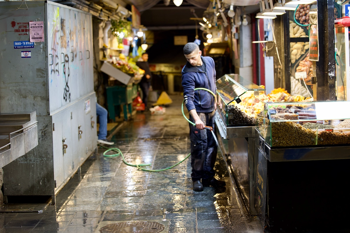 Worker hosing down Mahane Yehuda market at end of day