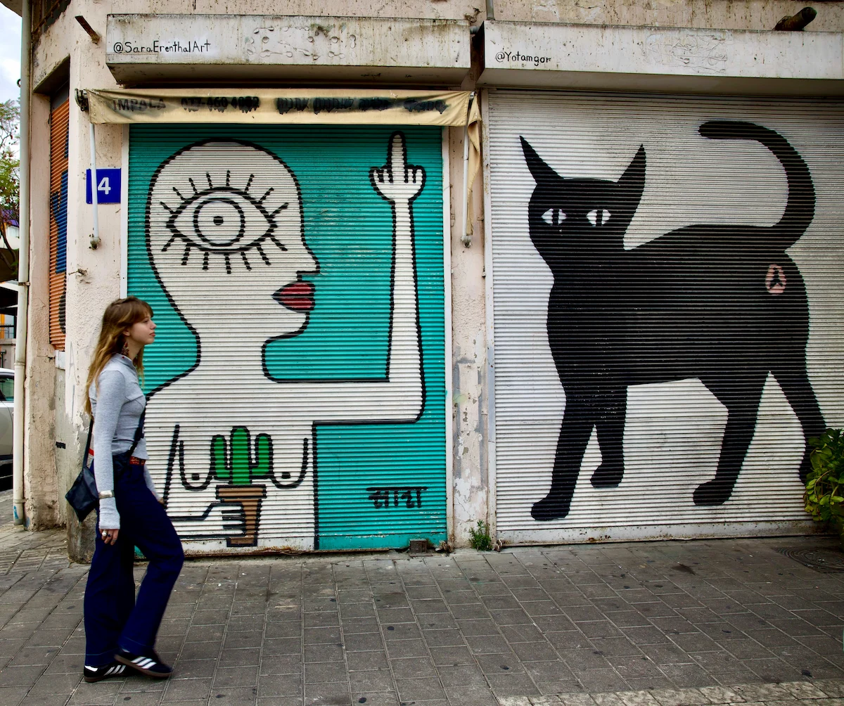 Woman walking past street art murals in Jaffa