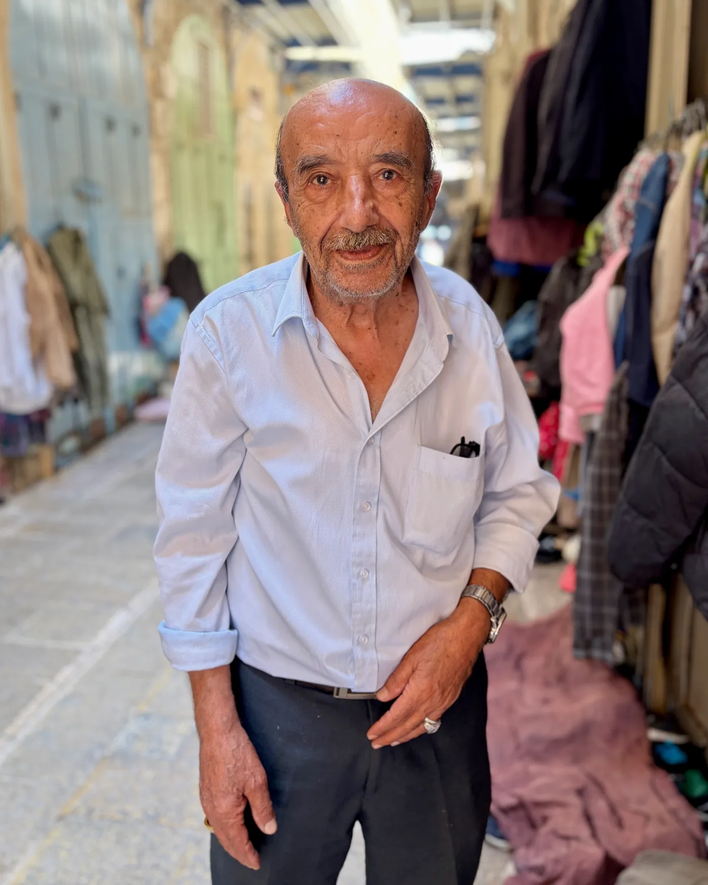Elderly man in a light blue shirt standing in a covered market lane, Old City, Jerusalem