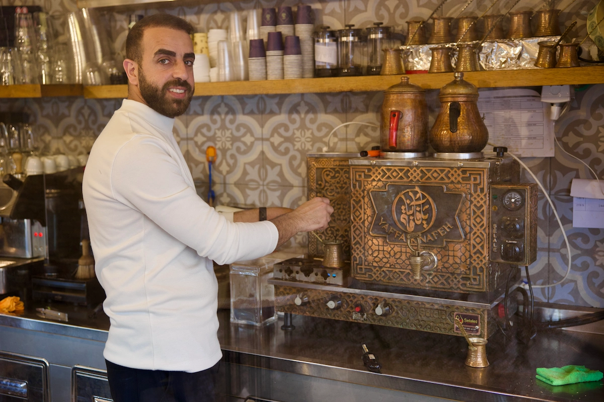 Man at Yaffa Knafeh café in Jaffa with ornate brass coffee machine